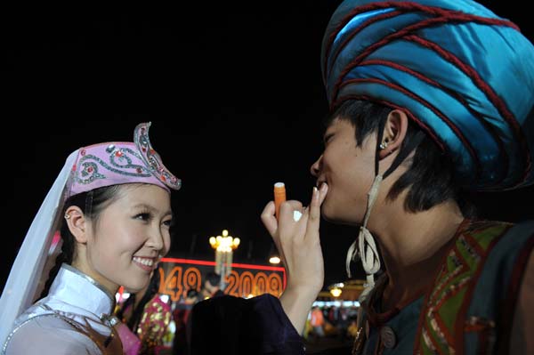 A performer puts on a bit of makeup for another performer before the grand performance in the celebrations for the 60th anniversary of the founding of the People's Republic of China, on the Tian'anmen Square in central Beijing, capital of China, October 1, 2009.