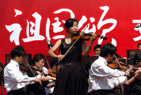 A violinist leads playing of the accompanying tune during a symphonic poem recitation show of Ode to Homeland, an outdoor public performance at the side of the West Lake with the musical obbligato by a symphony orchestra, in close range with the audience, in Hangzhou, capital of east China's Zhejiang Province, Oct. 2, 2009. (Xinhua/Shi Jianxue)