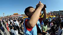 A boy takes photographs on the Tian'anmen Square in central Beijing, capital of China, on October 3, 2009.