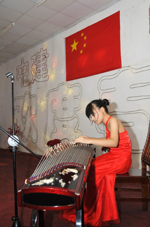 A girl of the art group of overseas Chinese in the United Arab Emirates (UAE) plays a seven-stringed zither, an old Chinese music instrument, during an evening party in Dubai of UAE, October 3, 2009. 