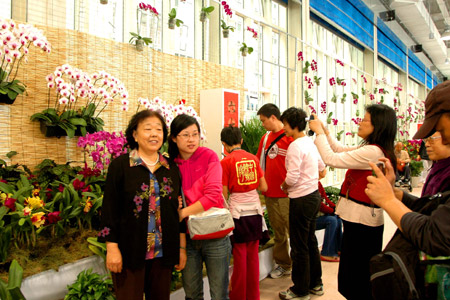 Visitors pose for photos at the exhibition hall of the seventh China Flower Expo in Shunyi District of Beijing, capital of China, October 3, 2009.