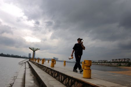 A security member patrols along the riverside at Jiangbin park in Fuzhou, capital of southeast China's Fujian Province, on October 5, 2009. As the approaching 17th tropical storm of the year Parma has brought gales to coastal areas of central and northern Fujian Province, local authorities were ordered to take precautions to ensure the safety of people and minimize losses. 