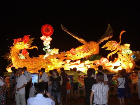 Tourists view a lantern group in the shape of phoenix, a traditional symbol of luck, auspiciousness and prosperity, during a lantern show in Haikou, capital of south China&apos;s Hainan Province, October 5, 2009. The lantern show was held at the Wanlu Garden in Haikou to greet the 60th anniversary of the founding of the People&apos;s Republic of China. 