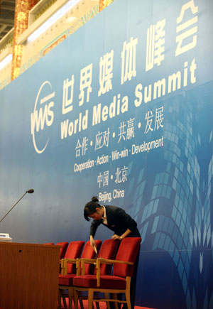 A staff member arranges chairs on the platform of the venue of the World Media Summit at the Great Hall of the People in Beijing, capital of China, on October 8, 2009. The preparation work was all done for the World Media Summit, which will be opened here on Friday morning with the attendance of heads of 135 media organizations from more than 70 countries and regions. 