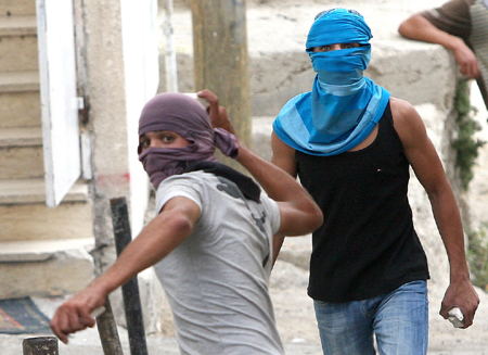 Arab protesters against Israel's decision to restrict entry into the Al-Aqsa Mosque, which is inside the holy site in the Old City, throw rocks at Israeli policemen in the East Jerusalem neighborhood of Ras el- Amud on October 9, 2009.