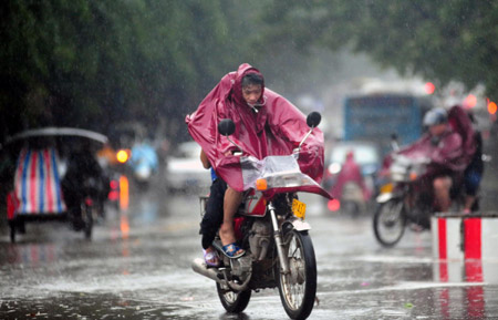 Motorcyclists shrouded in raincoats trudge ahead against gale and downpour on the street of Qionghai City, as the forefront of tropical storm Parma starts to affect south China's Hainan Province, October 12, 2009.