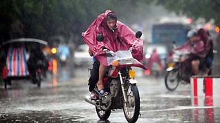 Motorcyclists shrouded in raincoats trudge ahead against gale and downpour on the street of Qionghai City, as the forefront of tropical storm Parma starts to affect south China's Hainan Province, October 12, 2009.