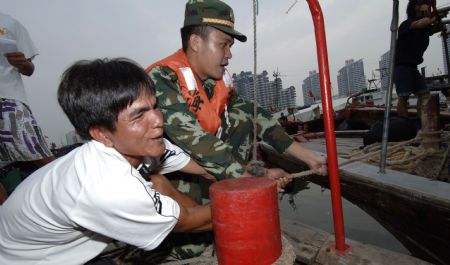Police in Sanya help the fisherfolks near the harbor of Sanya City, capital of south China's Hainan Province, October 11, 2009.