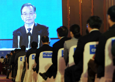 Participants watch a giant LCD when Chinese Premier Wen Jiabao is addressing a keynote speech during the opening ceremony of the 10th Western China International Economy and Trade Fair and the Second Western China Forum on International Cooperation in Chengdu, southwest China's Sichuan Province, October 16, 2009. 