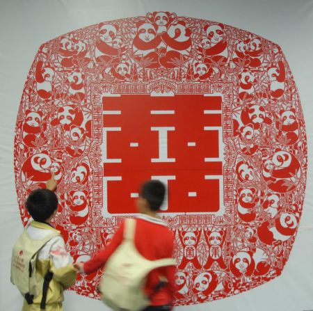 Two boys watch the paper-cutting artwork of double happiness by Zhang Zhuquan, a folk artist of paper-cutting of Tujia ethnic group, at the exhibition of Zhang Zhuquan personal paper-cutting artwork, where some 60 variously-designed double happiness paper-cutting and paper-carving artworks were on display at the Guiyang Art Gallery, in Guiyang, southwest China's Guizhou Province, October 17, 2009.