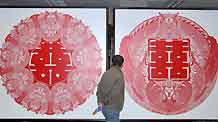 A visitor watches the paper-cutting artwork of double happiness by Zhang Zhuquan, a folk artist of paper-cutting of Tujia ethnic group, at the exhibition of Zhang Zhuquan personal paper-cutting artwork, where some 60 variously-designed double happiness paper-cutting and paper-carving artworks were on display at the Guiyang Art Gallery, in Guiyang, southwest China's Guizhou Province, October 17, 2009.
