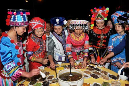 A bevy of women in florid ethnic costumes relish the savours of well-assorted ambrosia at the Folklore Food Festival, which lays emphasis on inheritance and carrying forward the characteristic culinary culture of indigenous ethnic minorities, tapping affluent cuisine resources and attach great importance for better preservation, in Wenshan County, Wenshan Zhuang and Miao Autonomous Prefecture, southwest China's Yunnan Province, October 20, 2009. 