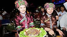 Two female in florid ethnic costumes show off the savoury dainties on the Folklore Food Festival, which lays emphasis on inheritance and carrying forward the characteristic culinary culture of indigenous ethnic minorities, tapping affluent cuisine resources and attach great importance for better preservation, in Wenshan County, Wenshan Zhuang and Miao Autonomous Prefecture, southwest China's Yunnan Province, October 20, 2009.