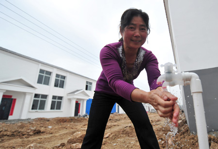 Li Chunmei, a resettler displaced by the North-to-South Water Diversion Project from Xijiadian Township, Danjiangkou City of northwest China's Hubei Province, smiles as she washes hands with tap water in front of her new house at the Yepo settlement, Jingmen city of Hubei Province, October 21, 2009. The 4th batch of 94 families of resettlers from Xijiadian Township moved into their new houses in Jingmen on Tuesday.