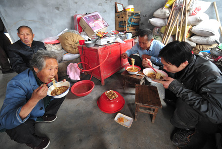Yuan Mingxiang, a resettler displaced by the North-to-South Water Diversion Project from Xijiadian Township, Danjiangkou City of northwest China's Hubei Province, has the first meal with family in his new house at the Yepo settlement, Jingmen city of Hubei Province, October 21, 2009. The 4th batch of 94 families of resettlers from Xijiadian Township moved into their new houses in Jingmen on Tuesday.