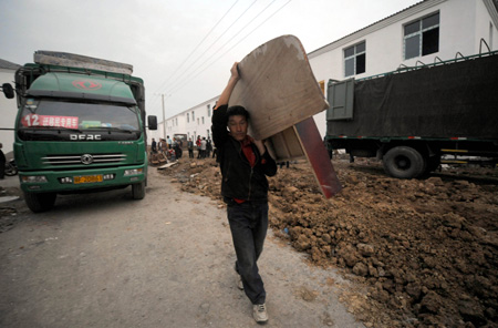 A resettler displaced by the North-to-South Water Diversion Project from Xijiadian Township, Danjiangkou City of northwest China's Hubei Province, carries a piece of furniture to his new house at the Yepo settlement, Jingmen city of Hubei Province, October 20, 2009. The 4th batch of 94 families of resettlers from Xijiadian Township moved into their new houses in Jingmen on Tuesday.