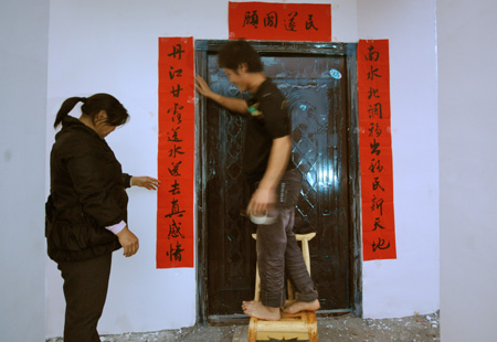 A couple of resettlers displaced by the North-to-South Water Diversion Project from Xijiadian Township, Danjiangkou City of northwest China's Hubei Province, paste couplets at the door of their new house at the Yepo settlement, Jingmen city of Hubei Province, October 20, 2009. The 4th batch of 94 families of resettlers from Xijiadian Township moved into their new houses in Jingmen on Tuesday.