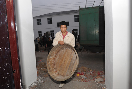 A resettler displaced by the North-to-South Water Diversion Project from Xijiadian Township, Danjiangkou City of northwest China's Hubei Province, carries a wooden basin to his new house at the Yepo settlement, Jingmen city of Hubei Province, October 20, 2009. The 4th batch of 94 families of resettlers from Xijiadian Township moved into their new houses in Jingmen on Tuesday.