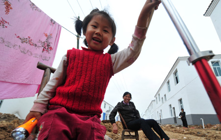 Zou Jiayi, a 4-year-old resettler displaced by the North-to-South Water Diversion Project from Xijiadian Township, Danjiangkou City of northwest China's Hubei Province, plays with her friends in front of a new house at the Yepo settlement, Jingmen city of Hubei Province, October 21, 2009. The 4th batch of 94 families of resettlers from Xijiadian Township moved into their new houses in Jingmen on Tuesday.