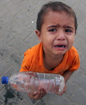 A Palestinian boy cries with a plastic bottle of drinking water in the southern Gaza Strip town of Rafah October 21, 2009.