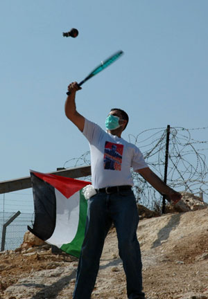 Palestinian demonstrators throw tear gas at Israeli troops during a demonstration against Israel's construction of a separation barrier in the West Bank village of Bilin near Ramallah, on October 23, 2009. 