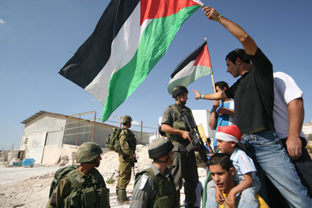 Israeli soldiers stand guard as Palestinian protesters take part in a demonstration against Israel's construction of a separation barrier in the West Bank village of Al-Maasara near Bethlehem, October 23, 2009. 