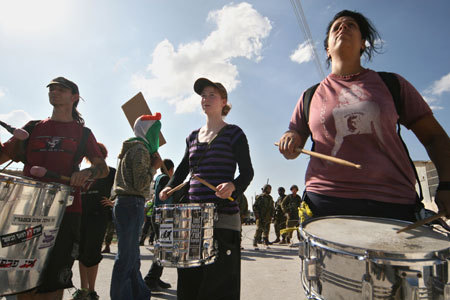 International peace activists play drums in front of Israeli soldiers during in a demonstration against Israel's construction of a separation barrier in the West Bank village of Al-Maasara near Bethlehem, October 23, 2009.