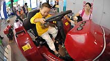 A child plays on an agricultural machine at the Nanning International Convention and Exhibition Center, which is the venue of the 6th China-ASEAN Expo, in Nanning, capital of southwest China's Guangxi Zhuang Autonomous Region, October 24, 2009.