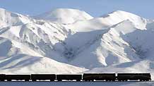 A train runs at the foot of snow-covered mountains in northwest China's Qinghai Province, October 24, 2009. The Qinghai-Tibet railway will enter its 4th winter operation after three year's safety running, which strongly boosted the economic and social developments in Qinghai and Tibet Autonomous Region.