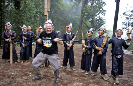 A foreign visitor jubilate together with local villagers of Miao ethnic group playing Luseng (a reed-pipe wind instrument), as local villagers of Miao ethnic group gather for a song and dance rendezvous in celebration of this autumn bumper harvest as a result of seasonable weather with gentle breeze and timely rainfalls, in Basha Village, Congjiang County, southwest China&apos;s Guizhou Province, October 24, 2009.