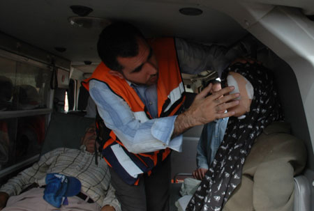 A Palestinian man medicates a Palestinian woman after several Palestinian farmers clash with Israeli settlers in the West Bank city of Nablus, October 27, 2009.