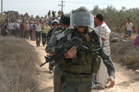 Israeli soldiers walks next to Palestinian farmers after several Palestinian farmers clash with Israeli settlers in the West Bank city of Nablus, October 27, 2009. 