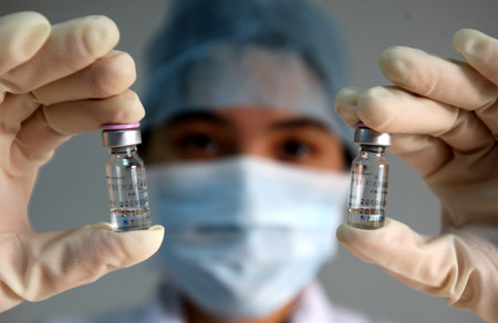 A medical staff with local center for disease control and prevention holds high two pyxises of vaccination against A/H1N1 flu virus, at Dongguan City, south China's Guangdong Province, October 28, 2009.