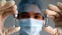 A medical staff with local center for disease control and prevention holds high two pyxises of vaccination against A/H1N1 flu virus, at Dongguan City, south China's Guangdong Province, October 28, 2009.