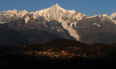 The village at the foot of Meili Snow Mountain is illuminated by sunlight in Deqin county, Diqing Tibetan Autonomous Prefecture, in southwest China's Yunnan Province, on October 27, 2009. 