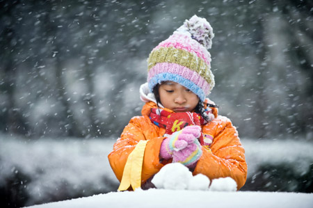 A girl makes snowballs in Beijing November 1, 2009. The city's first snowfall this winter started Saturday night, bringing fresh air to locals as well as a sharp drop in temperature.