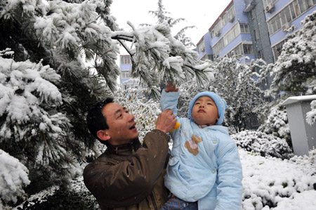 A father holds his son as they admire the snow in a neighborhood in Beijing November 1, 2009.