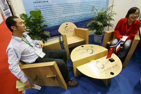 Two staff members show a set of table and chairs made of waste paper boxes at the 2009 Hangzhou International Recycling Economy and Environmental Industry Expo of China in Hangzhou, east China's Zhejiang Province, October 31, 2009. 