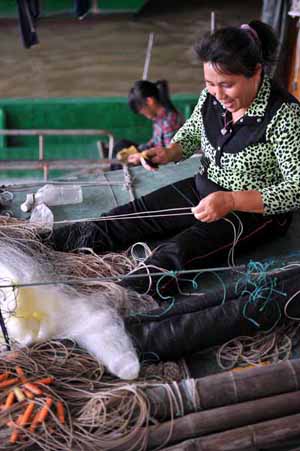 Fishermen repair fishing net in a port in Haikou, capital of south China's Hainan Province, November 2, 2009.
