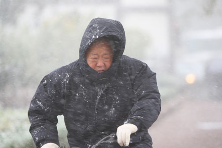 A citizen rides against wind on a street in Yantai, east China's Shandong Province, November 2, 2009. A cold front hit Yantai on Monday, bringing sharp drop of temperatures and snow in the city. 
