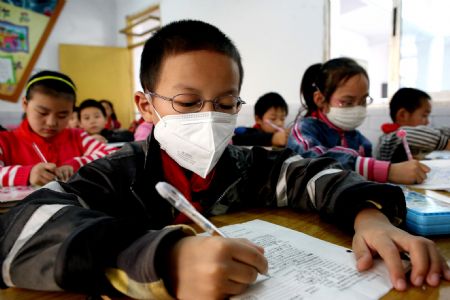 A boy wears a face mask on the class in Shuanghe Elementary School in Huaying, southwest China's Sichuan Province, November 3, 2009.