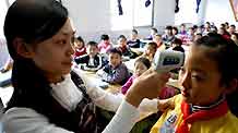 A teacher takes the temperature of a girl during the class break in Shuanghe Elementary School in Huaying, southwest China's Sichuan Province, November 3, 2009. Over 3,200 students in Shuanghe Elementary School resumed classes except some staying home for further observation. The school has been closed for ten days as several students infected A/H1N1 flu. Some other local schools in the same situation have also resumed classes in succession.