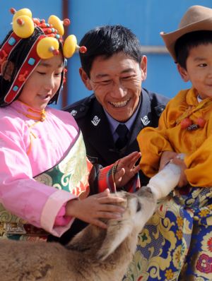 Ceyun Bainco (L), her father Muma Zhaxi (C) and her brother feed a young Tibetan antelope at Sonam Daje Natural Protection Station in Hol Xil Natural Reserve in Northwest China