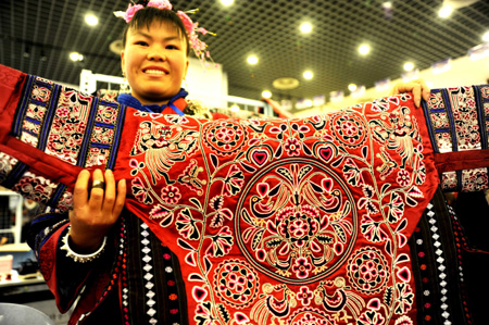 A woman of the Miao ethnic group shows her own hand-stitched exquisite brocade garb, on the 2009 'Colorful Guizhou' Tourist Commodities Design Competition and Final Selection Campaign of Skillful Craftsmen in Designing Tourist Commodities, in Guiyang, southwest China's Guizhou Province, November 3, 2009.