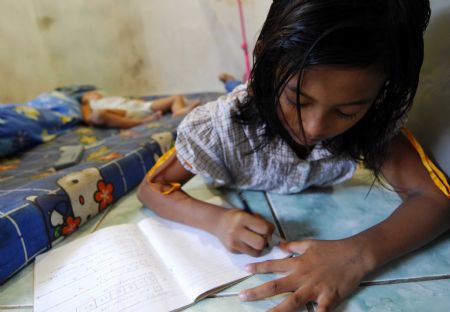 Indonesian girl Nurul, nine-year-old, does her homework while her younger brother is asleep in Jakarta October 25, 2009.