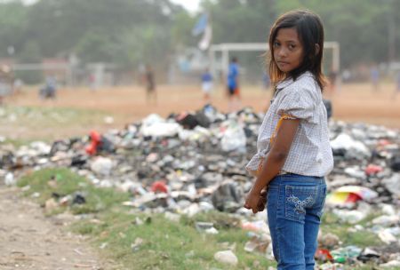 Indonesian girl Nurul, nine-year-old, walks past a pile of garbage near a slum area in Jakarta October 25, 2009.