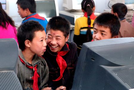 Liu Lei (C, front) gets excited after typing his name on the computer for the first time at Jinfengliangtian Primary School in Yinchuan, northwest China's Ningxia Hui Autonomous Region, in the file photo taken on October 18, 2006, the day the Hope cyber school of Jinfengliangtian Primary School opened. 