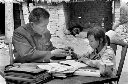 Hu Zunxun (L), a teacher of Jinzhai County Hope Primary School, tutors his student Hu Yali to make up the lessons she had missed in Jinzhai County, east China's Anhui Province, in this file photo taken on May, 1991. Hu Zunxun travel over 10 kilometers to help Hu Yali as she had discontinued her study for one year.