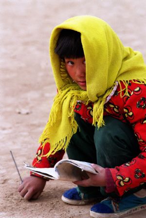 A girl practices writing with a stick on the ground at a primary school in Wanyaozi village, Lintao County, northwest China's Gansu Province, in December, 1998. Many children in this village went back to school with the help of Hope Project. 