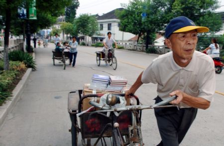 Zhou Huosheng, a 73-year-old retired teacher, sells books with a tricycle in Qiandeng town, Kunshan city, east China's Jiangsu Province, in this photo taken on September 7, 2006. Zhou Huosheng has been using his savings and income raised by selling books to help the dropouts in the mountainous area since 1994.